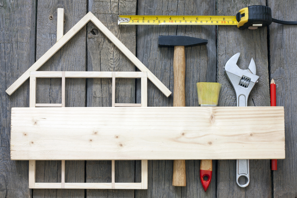 Wooden house model on table with construction tools